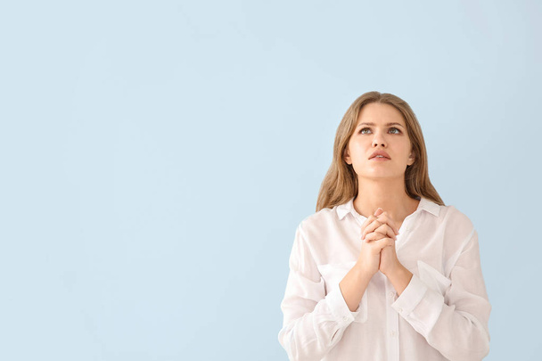 Religious young woman praying to God on light color background - 写真・画像