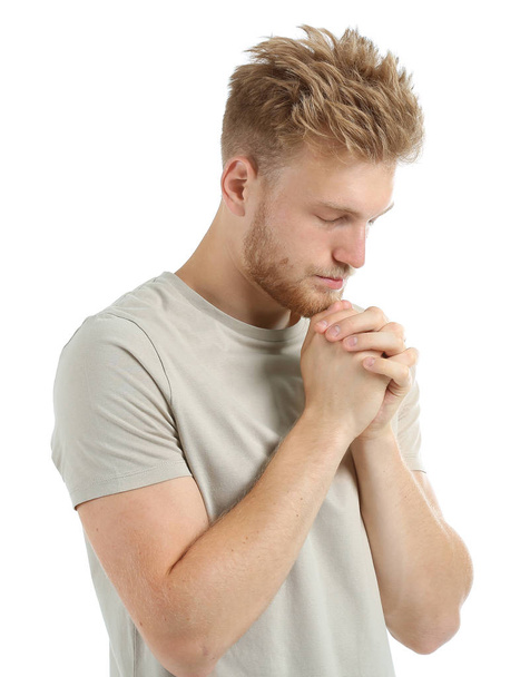 Religious young man praying to God on white background - Foto, afbeelding