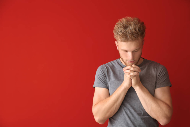 Religijny młodzieniec modlący się do Boga na kolorowym tle - Zdjęcie, obraz