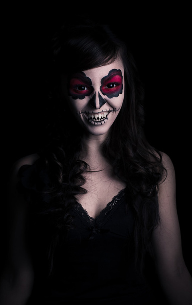 Retrato bajo de mujer joven oliendo con maquillaje de cráneo de azúcar
 - Foto, Imagen