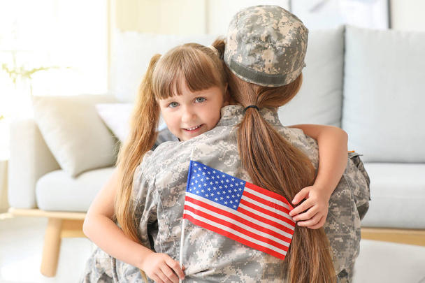 Happy female soldier of USA army hugging her little daughter at home - Photo, Image
