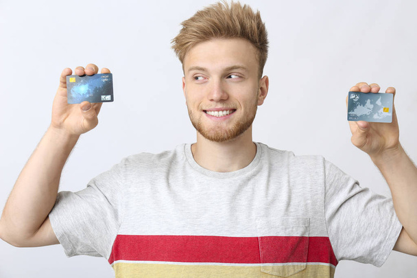 Joven feliz con tarjetas de crédito sobre fondo blanco
 - Foto, Imagen