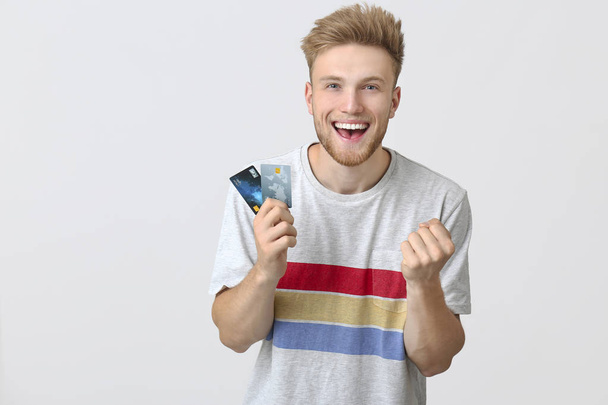 白い背景にクレジットカードを持つ幸せな若者 - 写真・画像
