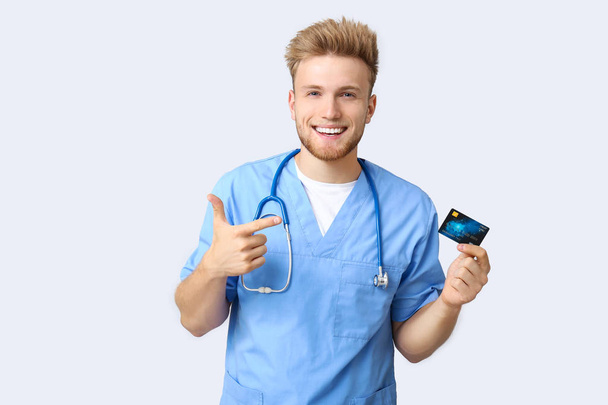 Happy male doctor with credit card on white background - Photo, Image
