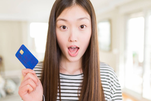Kredi kartı tutan güzel Asyalı kadın sürpriz bir yüzle şokta korkmuş, korku yla korkmuş ve heyecanlı ifade - Fotoğraf, Görsel