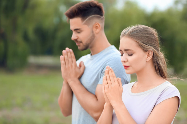 Young couple praying to God outdoors - 写真・画像