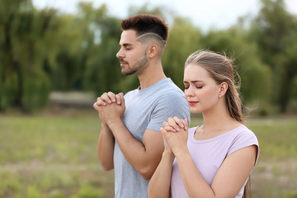 Young couple praying to God outdoors - Foto, imagen