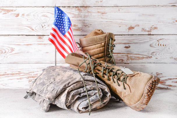 Military uniform and USA flag on table against wooden background - Foto, imagen
