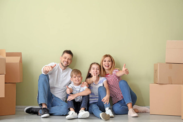Famille heureuse avec des effets montrant geste pouce vers le haut dans leur nouvelle maison
 - Photo, image