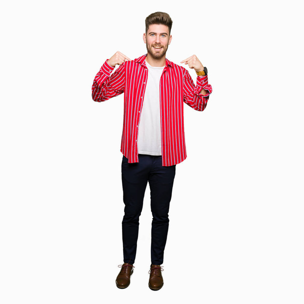Fiatal jóképű férfi visel piros inget keres magabiztos mosollyal az arcon, rámutatva magát ujjaival büszke és boldog. - Fotó, kép