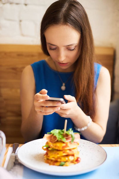 Молодая красивая женщина держит мобильный телефон в руках, ожидая своих друзей
 - Фото, изображение
