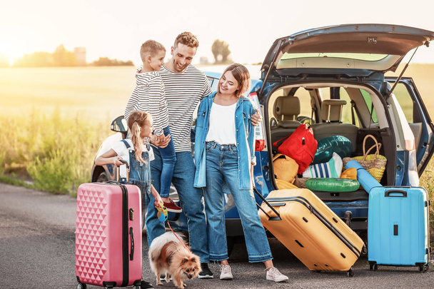 Onnellinen perhe matkatavaroiden kanssa auton lähellä ulkona
 - Valokuva, kuva