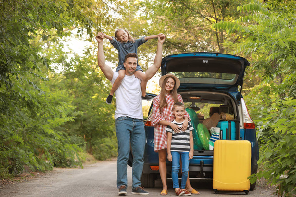 Onnellinen perhe lähellä autoa matkatavaroiden kanssa ulkona
 - Valokuva, kuva