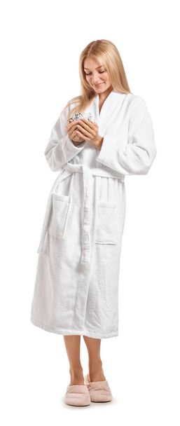 Beautiful young woman in bathrobe drinking coffee on white background - Photo, Image