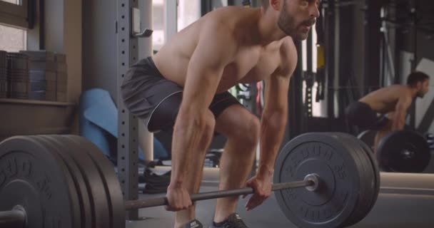 Closeup portrait of shirtless muscular caucasian man lifting weights being determined in the gym indoors - Video