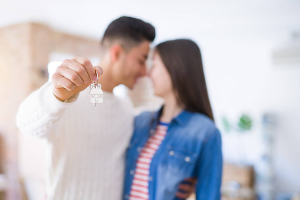 Молодая пара, держа в руках ключи от нового дома, улыбается счастливо и взволнованно переезжая в новую квартиру
 - Фото, изображение
