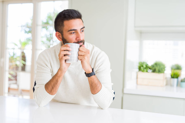 Handsome man smiling while enjoying drinking a cup of coffee in  - Photo, Image