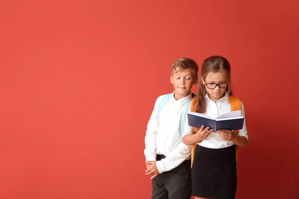 Little pupils with book on color background - Photo, Image