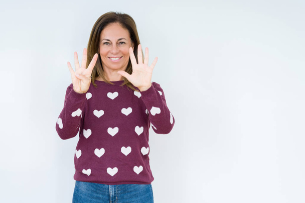 Mulher de meia-idade bonita vestindo suéter do coração sobre fundo isolado mostrando e apontando para cima com os dedos número nove, sorrindo confiante e feliz
. - Foto, Imagem