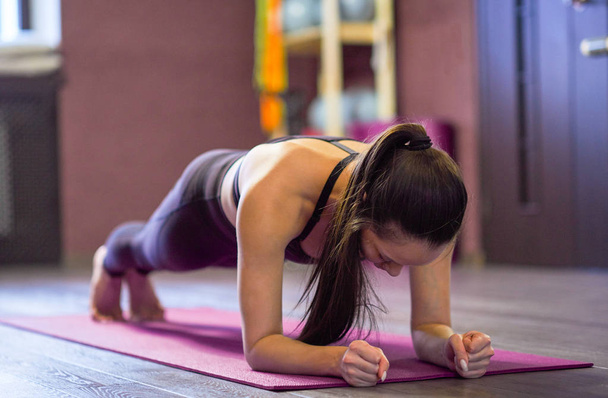 Workout, sport. Woman in the gym. young Asian girl with long hair performs the bar in a sports studio - Фото, зображення