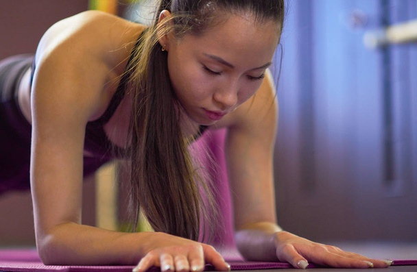 Тренировка, спорт. Женщина в спортзале. молодая азиатка с длинными волосами выступает в баре в спортивной студии
 - Фото, изображение