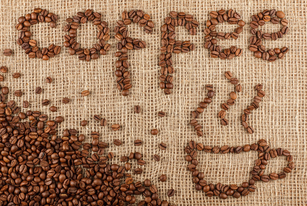 Coffee title with cup laid out from coffee beans on a burlap pattern. - Fotó, kép