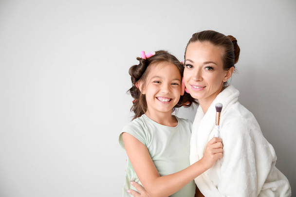 Portrait of happy mother with cute daughter on light background - Фото, зображення