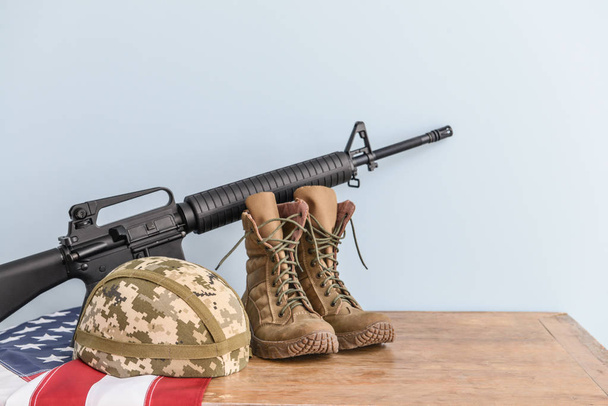 Militärhelm, Stiefel, Sturmgewehr und US-Fahne auf dem Tisch - Foto, Bild