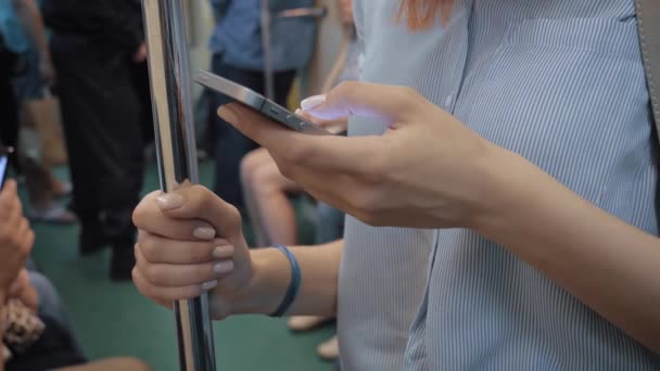 Las manos de la mujer usando aplicaciones de teléfonos inteligentes de pie en el vagón del metro con muchos pasajeros
 - Imágenes, Vídeo