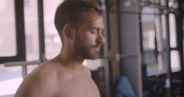 Closeup portrait of shirtless attractive caucasian man looking at camera smiling happily standing in the gym indoors - Video
