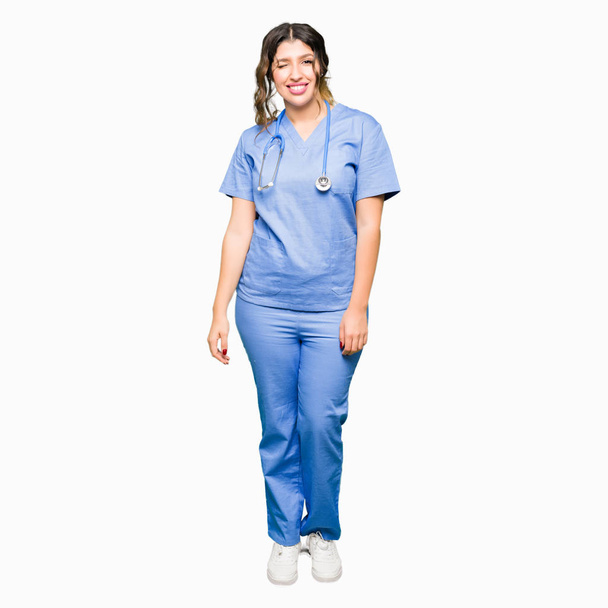 junge erwachsene Ärztin in medizinischer Uniform zwinkert in die Kamera mit sexy Ausdruck, fröhlichem und glücklichem Gesicht. - Foto, Bild