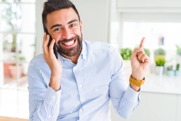 Komea latino liikemies, jolla on keskustelu puhuminen älypuhelimella erittäin onnellinen osoittaa käsin ja sormella sivulle
 - Valokuva, kuva