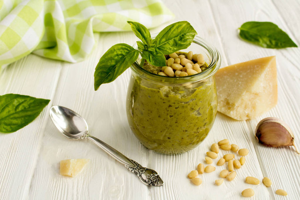 Pesto sauce dans le bocal en verre et ingrédients sur le fond en bois blanc
 - Photo, image