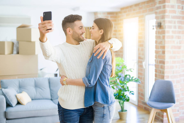 Yeni daire akıllı telefon kullanarak bir selfie fotoğraf çekerken güzel çift, yeni ev için mutlu gülümseyen - Fotoğraf, Görsel