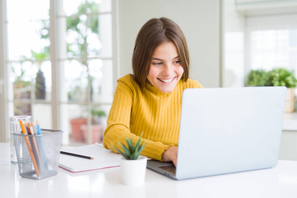 Kaunis nuori tyttö opiskelee kouluun tietokoneella kannettavan kanssa onnellinen kasvot seisoo ja hymyilee luottavainen hymy osoittaa hampaat
 - Valokuva, kuva