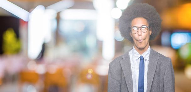Fiatal afro-amerikai üzletember a afro haj viselt szemüveg így hal arc, ajkak, őrült és komikus gesztus. Vicces kifejezés. - Fotó, kép