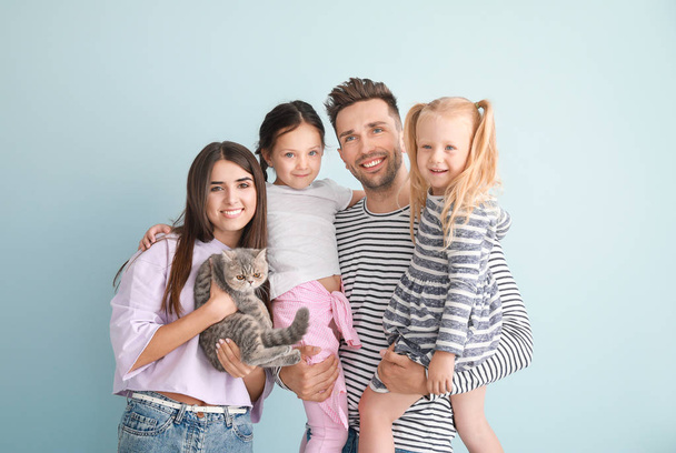 Happy family with cute cat on light background - Photo, Image