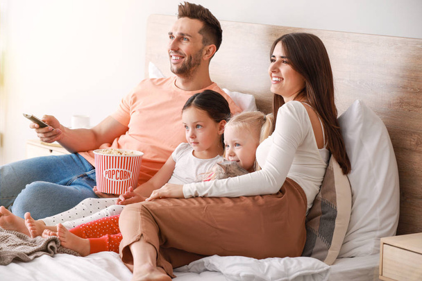Щаслива сім'я дивиться телевізор на ліжко вдома
 - Фото, зображення