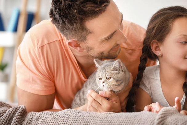 glückliche Familie mit süßer Katze zu Hause im Bett liegend - Foto, Bild