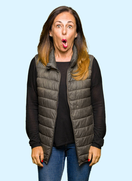 Красивая женщина средних лет в зимнем жилете в шокирующем лице, выглядит скептически и саркастично, удивлена с открытым ртом
 - Фото, изображение