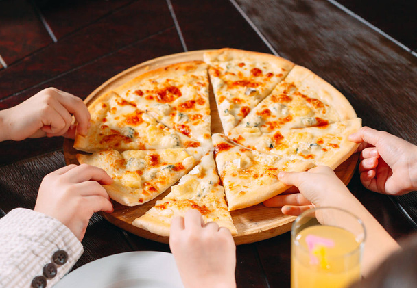Hands taking pizza slices from wooden table, close up view - Foto, imagen