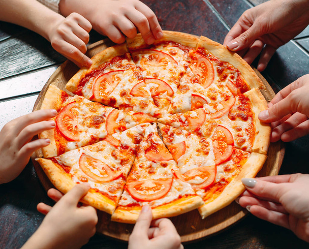 Hands taking pizza slices from wooden table, close up view. - Foto, immagini