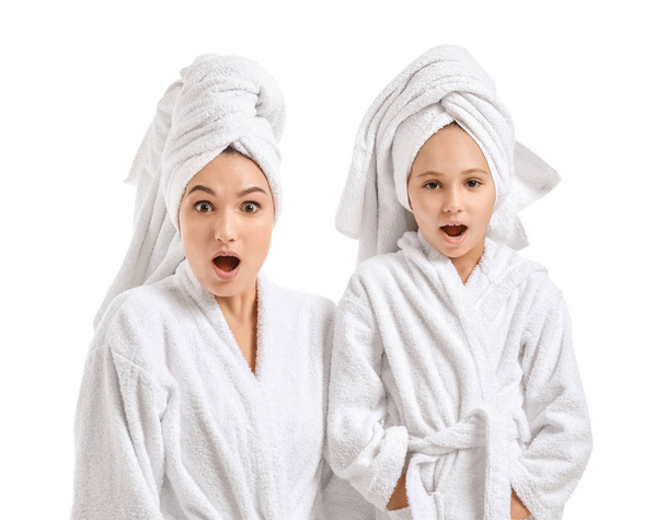 überraschte Mutter und ihre kleine Tochter in Bademänteln auf weißem Hintergrund - Foto, Bild