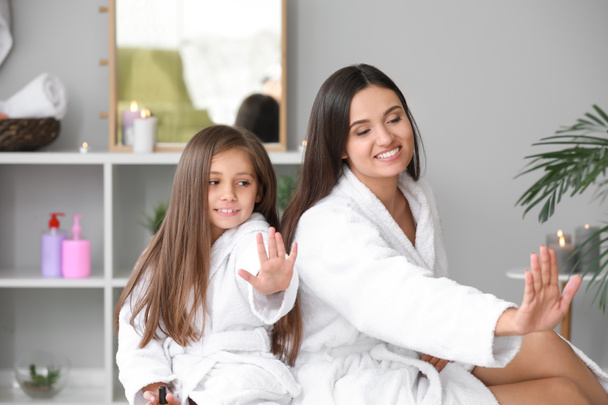 Мати і її маленька дочка в банні халати роблять нігті в домашніх умовах - Фото, зображення