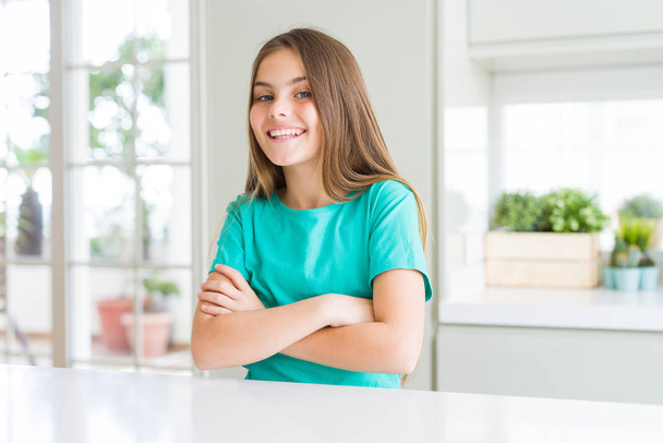 Kaunis nuori tyttö lapsi yllään vihreä t-paita iloinen kasvot hymyillen ristissä kädet katsoen kameraan. Positiivinen henkilö
. - Valokuva, kuva