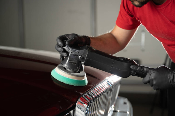Car detailing - man with orbital polisher in auto repair shop. vintage old car - Photo, image