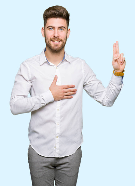 Joven hombre de negocios guapo jurando con la mano en el pecho y los dedos, haciendo una promesa de lealtad juramento
 - Foto, Imagen