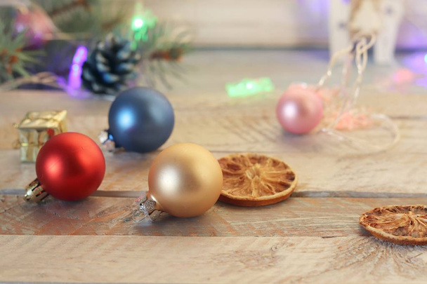Διακόσμηση, φωτισμένο χριστουγεννιάτικο δέντρο, Χριστουγεννιάτικα παιχνίδια και φέτες αποξηραμένου λεμονιού σε ξύλινο τραπέζι, εποχιακές χειμερινές διακοπές - Φωτογραφία, εικόνα