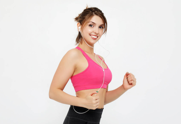 portrait of a smiling fitness woman in headphones working out isolated over white background - Φωτογραφία, εικόνα