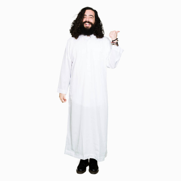Homme portant Jésus Christ costume souriant avec le visage heureux regardant et pointant vers le côté avec le pouce vers le haut
. - Photo, image